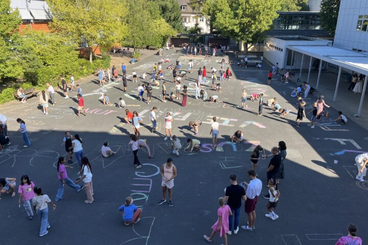 Schülerinnen und Schüler gestalten den Schulhof mit bunter Kreide und schreiben ihre wichtigsten Werte auf den Boden.